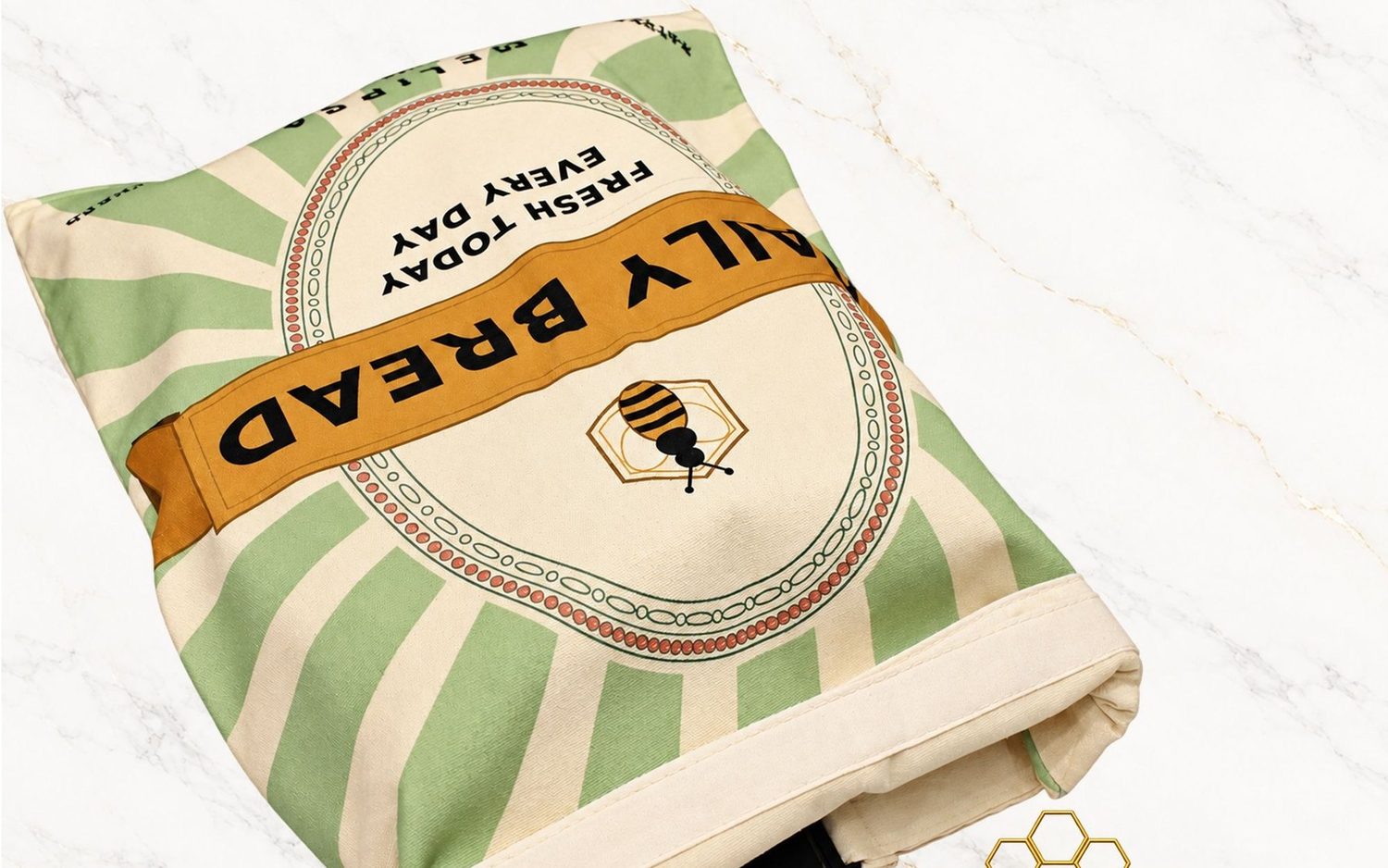 A folded Melipsa beeswax-lined bread bag in green, printed with the Daily Bread sunburst design