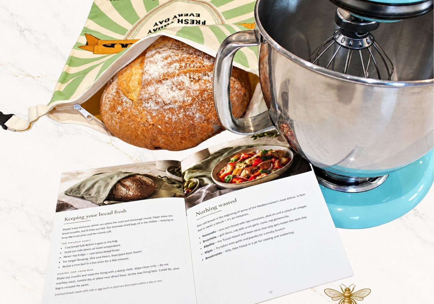 A round sourdough loaf inside an open Melipsa beeswax-lined bread bag on a marble worktop